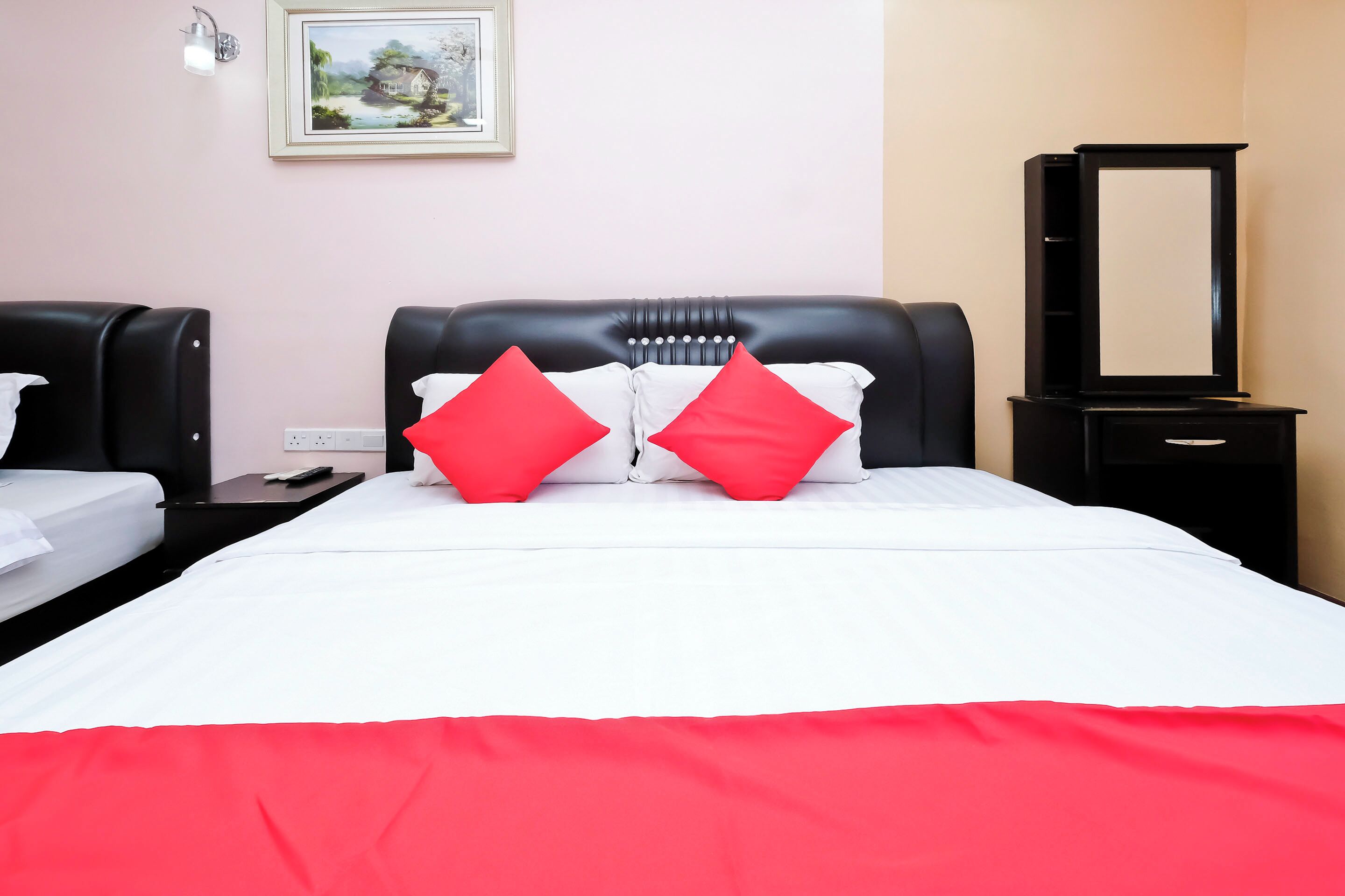 Een hotelkamer met een bed, twee nachtkastjes, een spiegel en een schilderij aan de muur.
