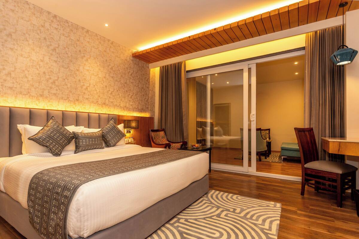 Ein geräumiges Schlafzimmer mit einem großen Bett, einer Schiebetür zum Balkon und einer Holzbalkendecke.