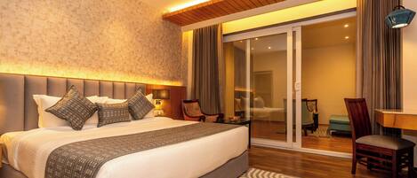 Un dormitorio espacioso con una cama grande, una puerta corredera de vidrio que da a un balcón y un techo de madera.
