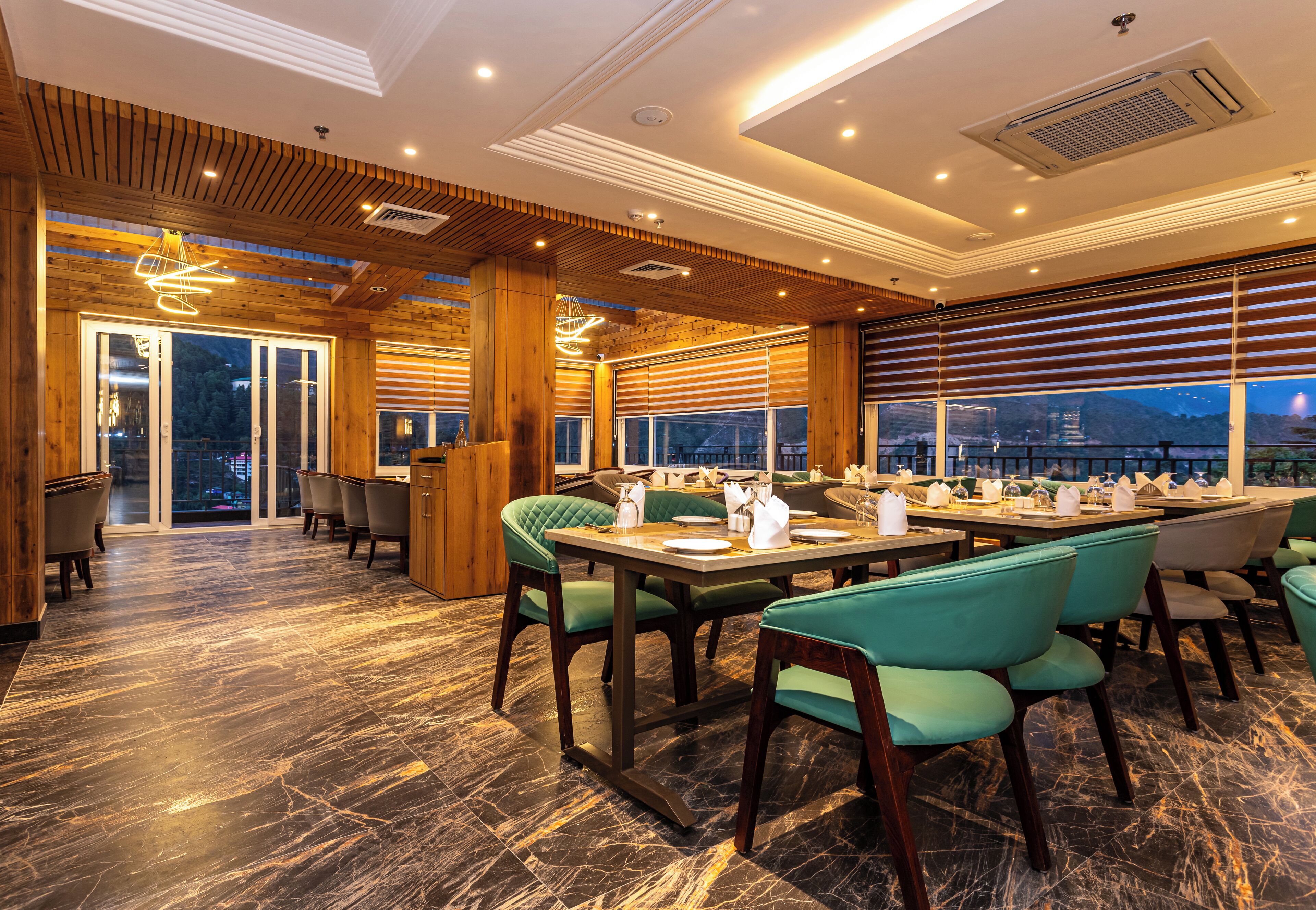 A restaurant with wooden paneling, green upholstered chairs, and a marble floor.