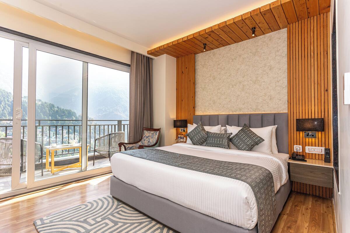 Ein modernes Schlafzimmer mit einem großen Bett, einem Fernseher und einem Balkon mit Blick auf die Berge.