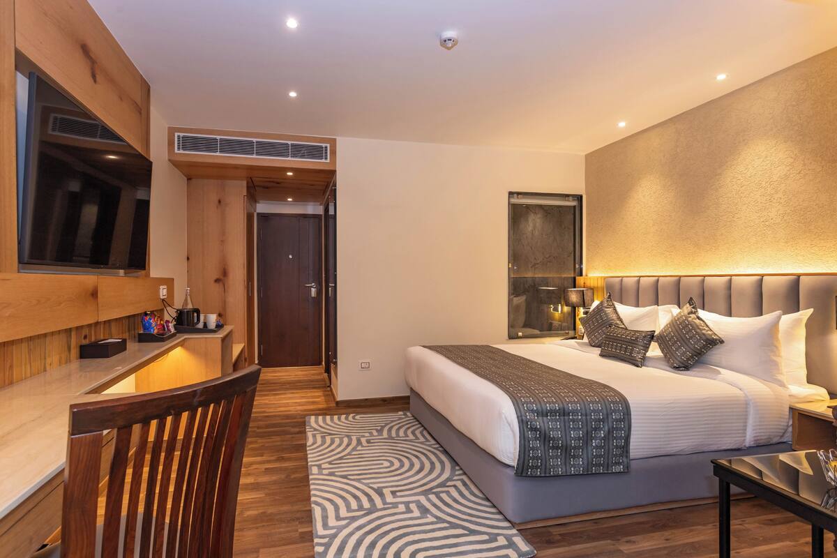 Ein modernes Hotelzimmer mit einem großen Bett, einem Schreibtisch mit Stuhl und einem Fernseher.