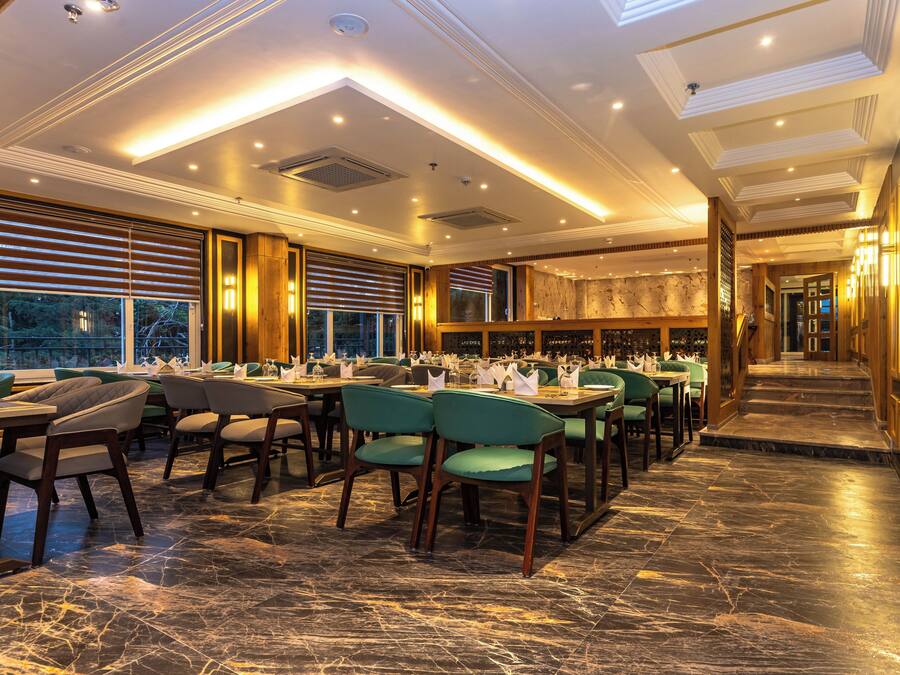 Ein geräumiges Restaurant mit hohen Decken, Marmorböden und verschiedenen Sitzgelegenheiten, darunter Boxen und Tische.
