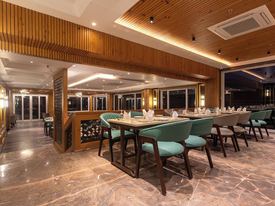 A restaurant with a wooden ceiling, marble flooring, and teal chairs.