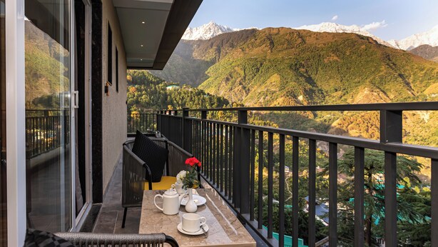 A balcony with a table set for tea, overlooking a mountainous landscape.
