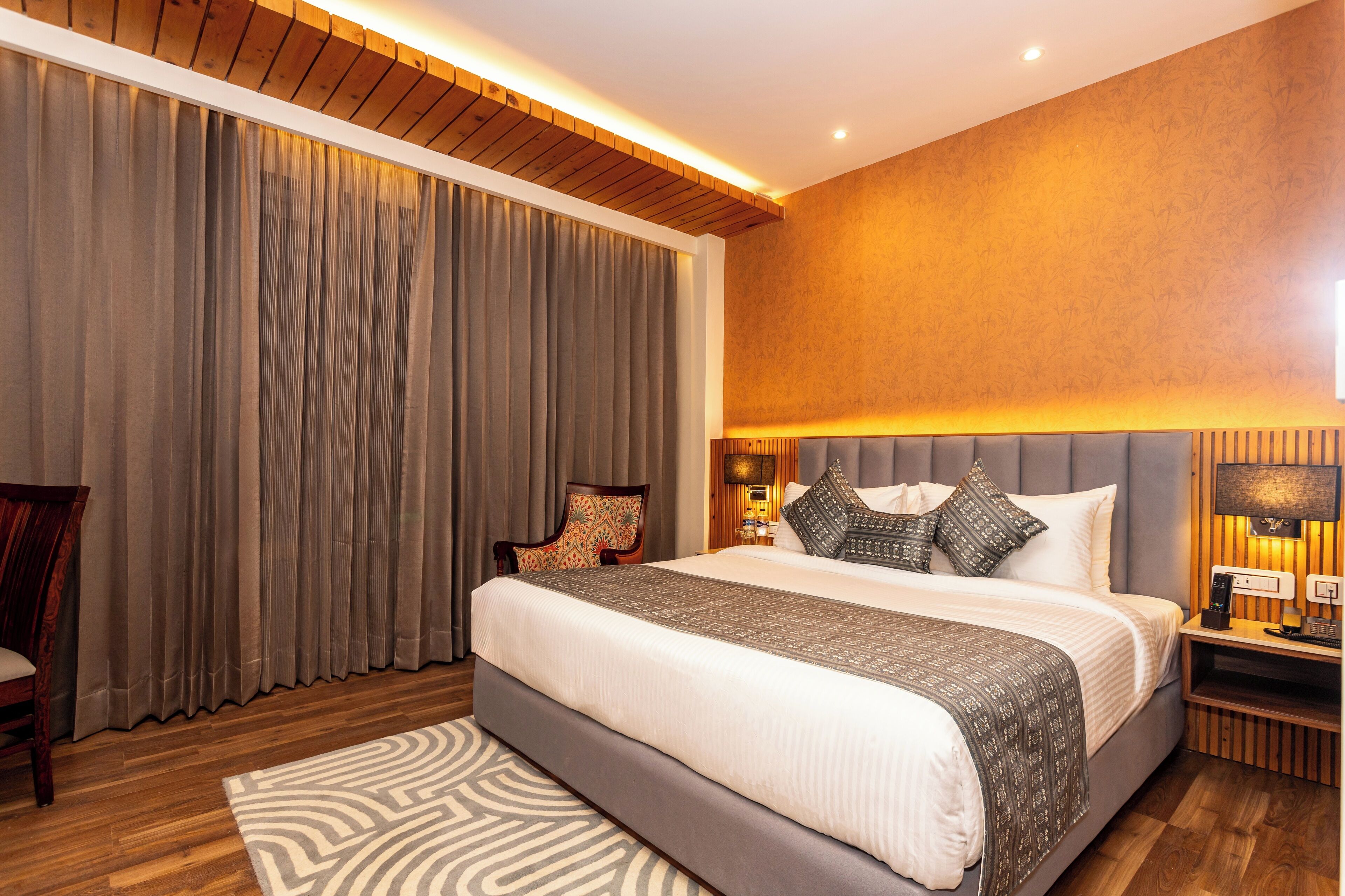 Una habitación de hotel moderna con una cama grande, techo de madera y una mesita de noche con lámpara.