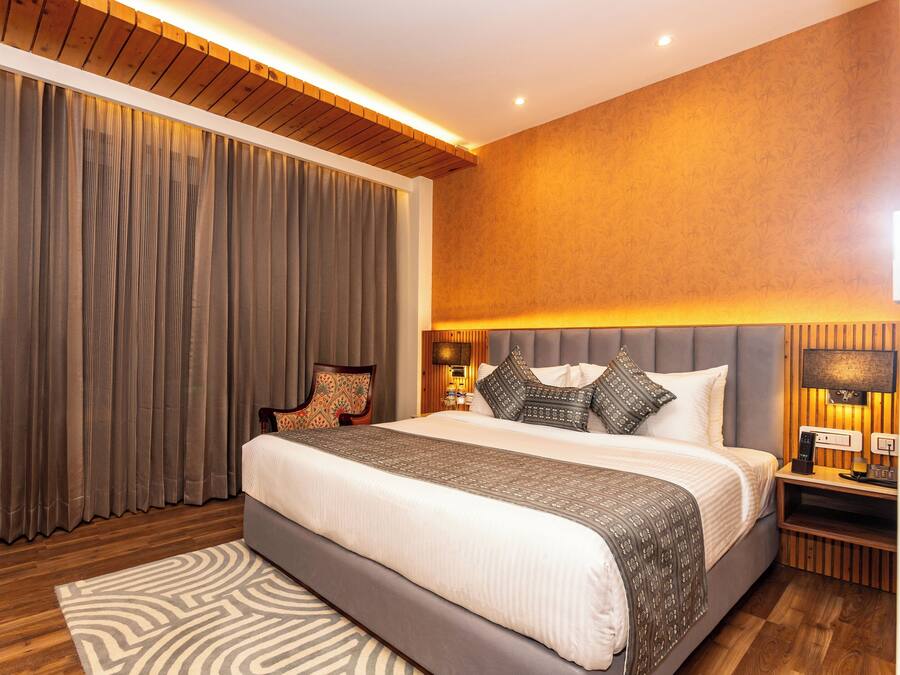 Una habitación de hotel moderna con una cama grande, techo de madera y una mesita de noche con lámpara.