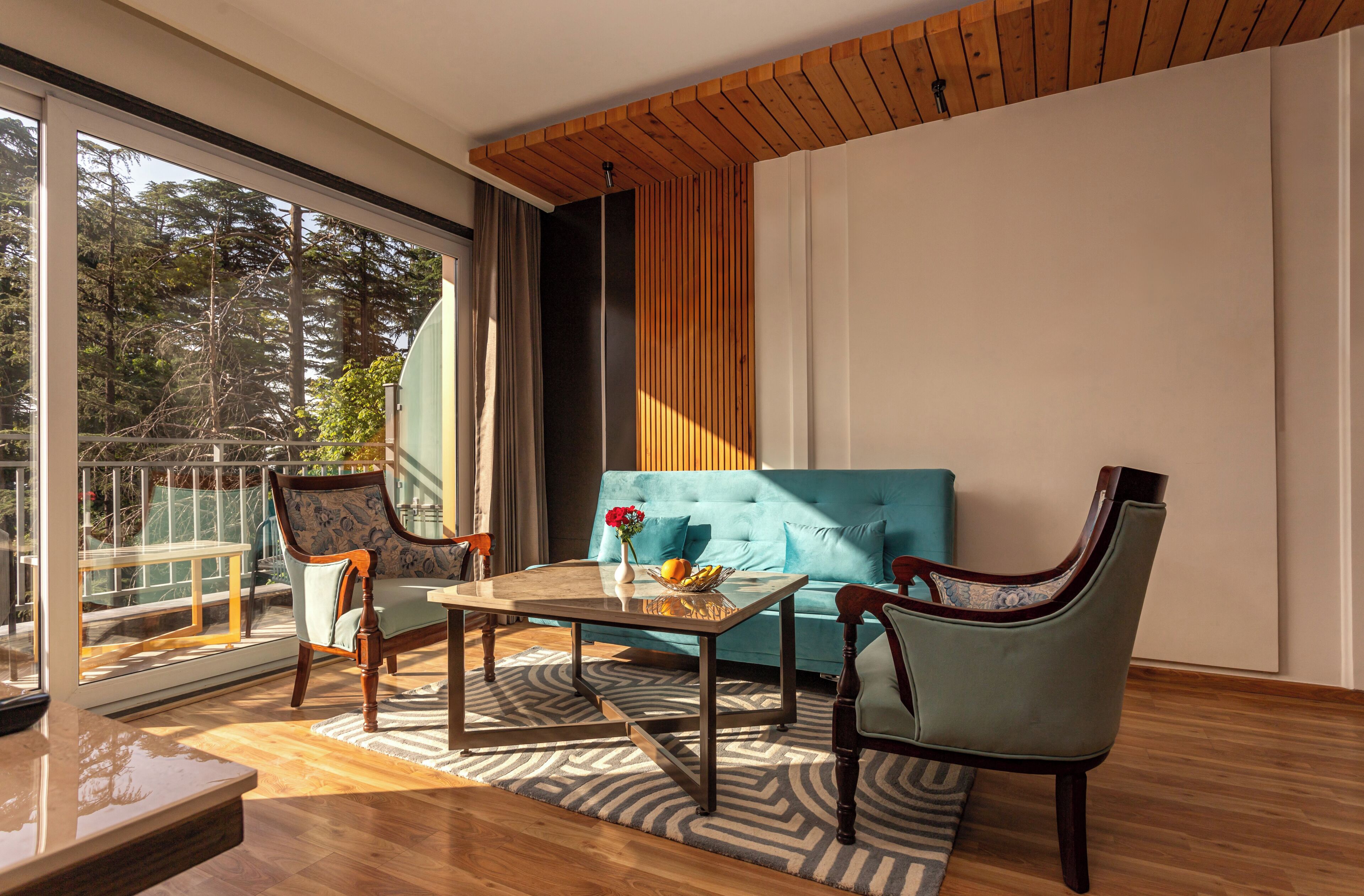 A modern living room with a sofa, two chairs, a coffee table, and a large window with a view of trees.
