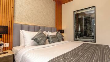 A bedroom with a large bed, a wooden headboard, a mirror, and a nightstand with a lamp and a bottle.