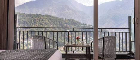 A balcony with a bed, a table with a vase of flowers, and chairs.