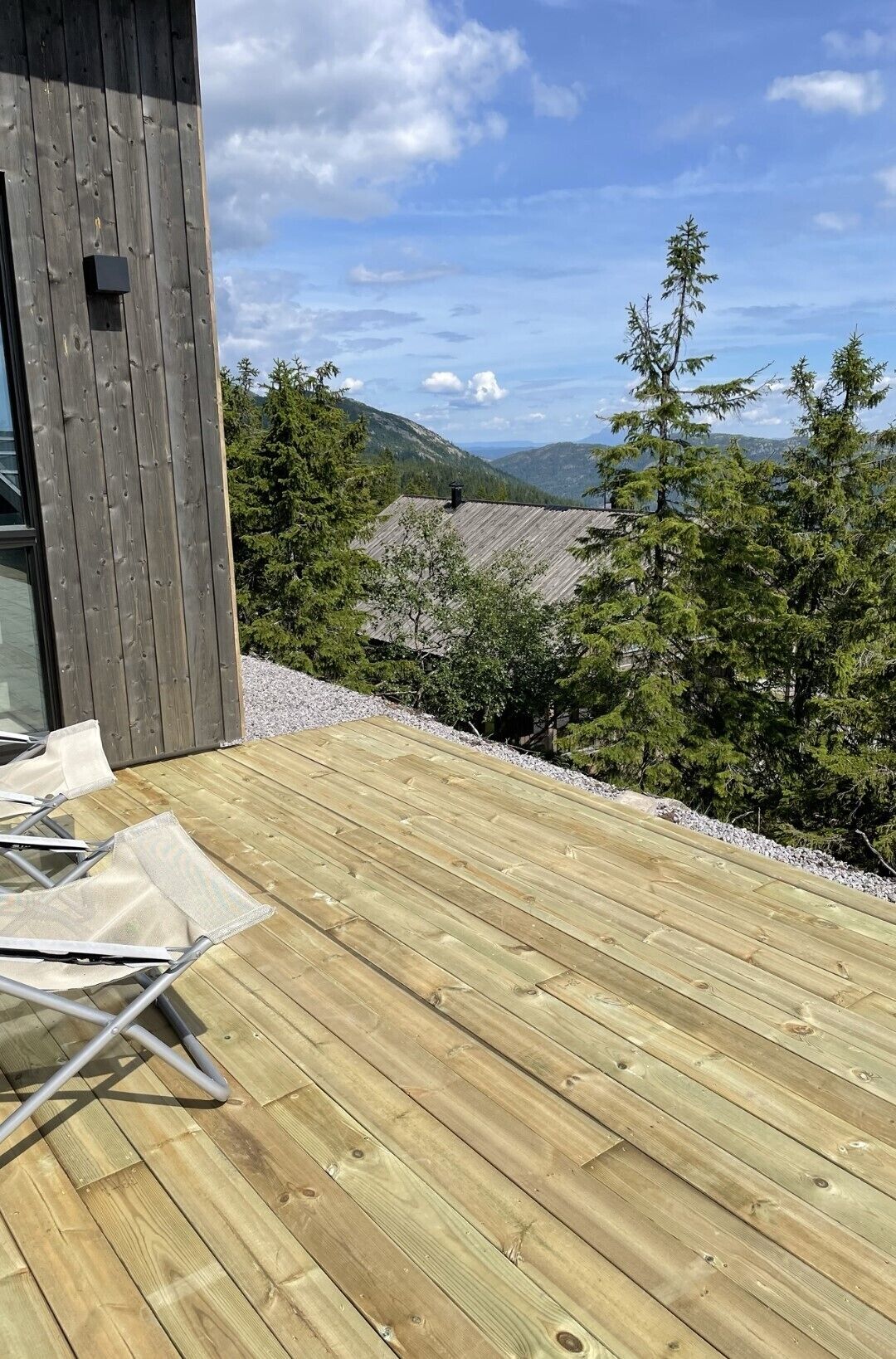 Une terrasse en bois offrant une vue sur une chaîne de montagnes et des arbres.