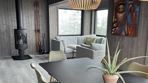 En moderne stue med et stort spisebord, behagelige siddepladser, en pejs og et stort vindue, der giver naturligt lys.