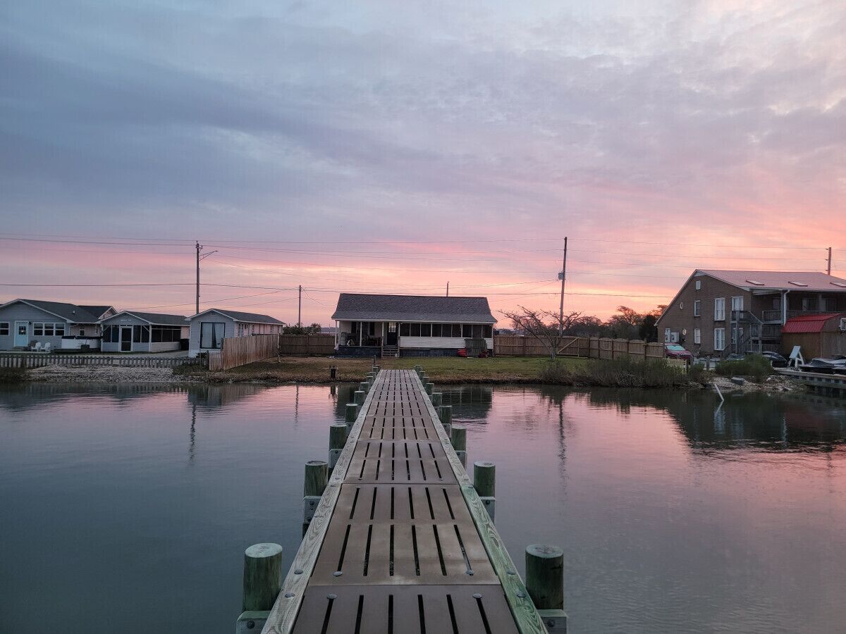 A wooden pier leading to a row of houses by a calm body of water.