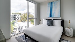 A modern bedroom with a large bed, a city view, and a blue abstract painting. - Kasa Wynwood Miami (Miami)