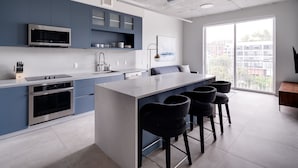 A modern kitchen with a central island, bar stools, and a large window with a city view. - Kasa Wynwood Miami (Miami)
