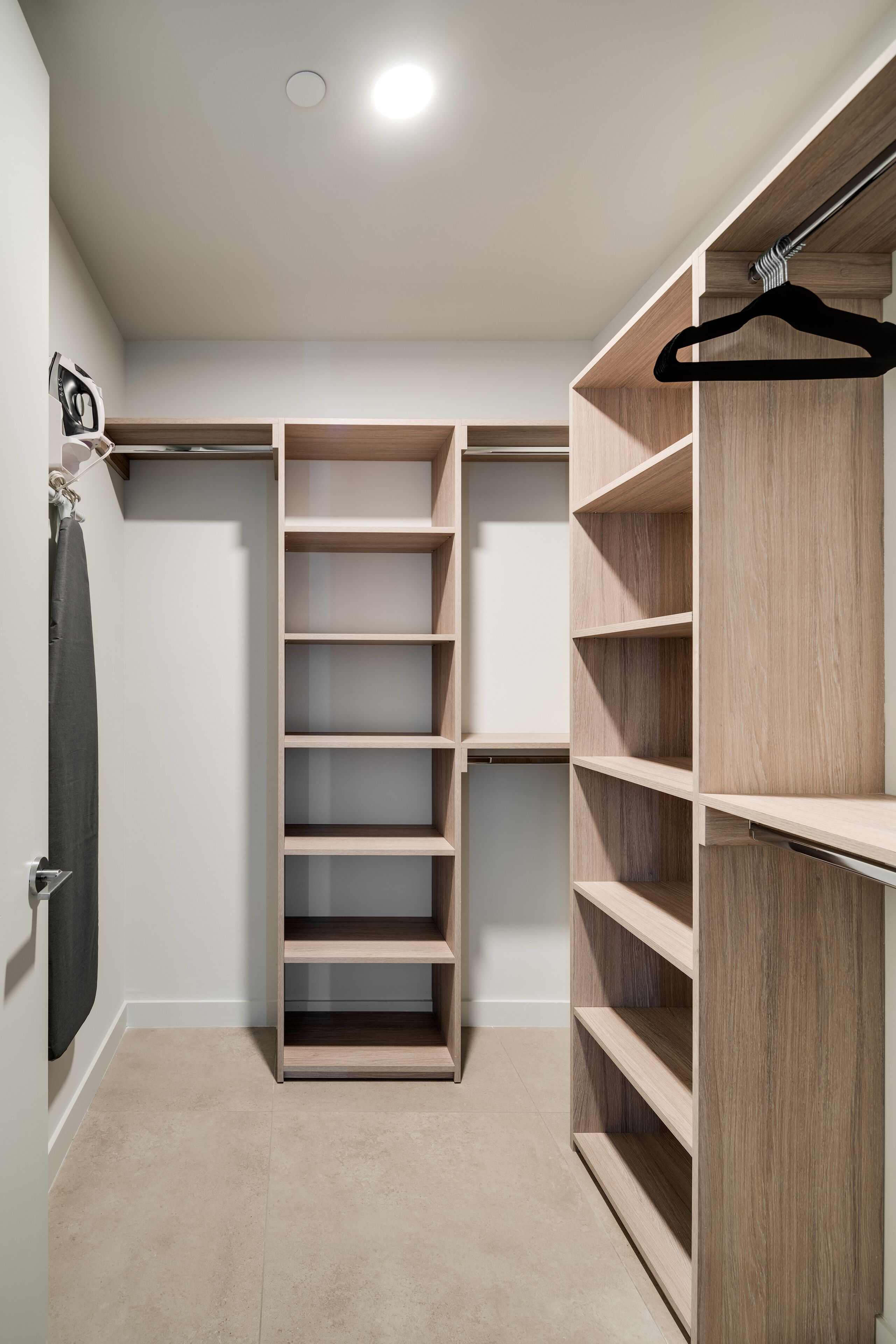 Ein begehbarer Kleiderschrank mit mehreren Holzböden und einer Kleiderstange.