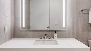 Un baño moderno con un espejo grande, lavamanos blanco y armarios de madera.
