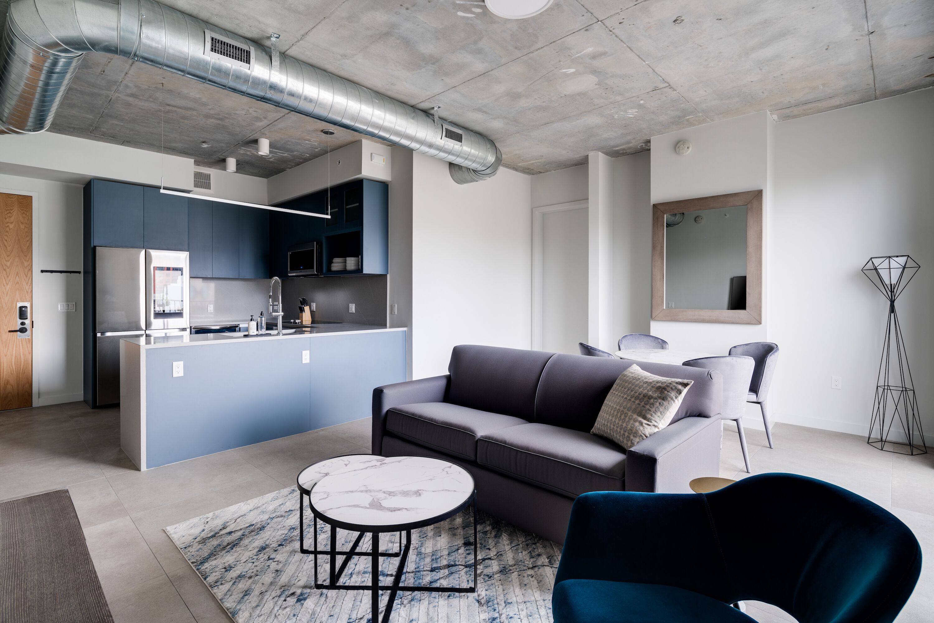 Un espace de vie moderne comprenant une cuisine, un canapé, une table basse et un lampadaire.