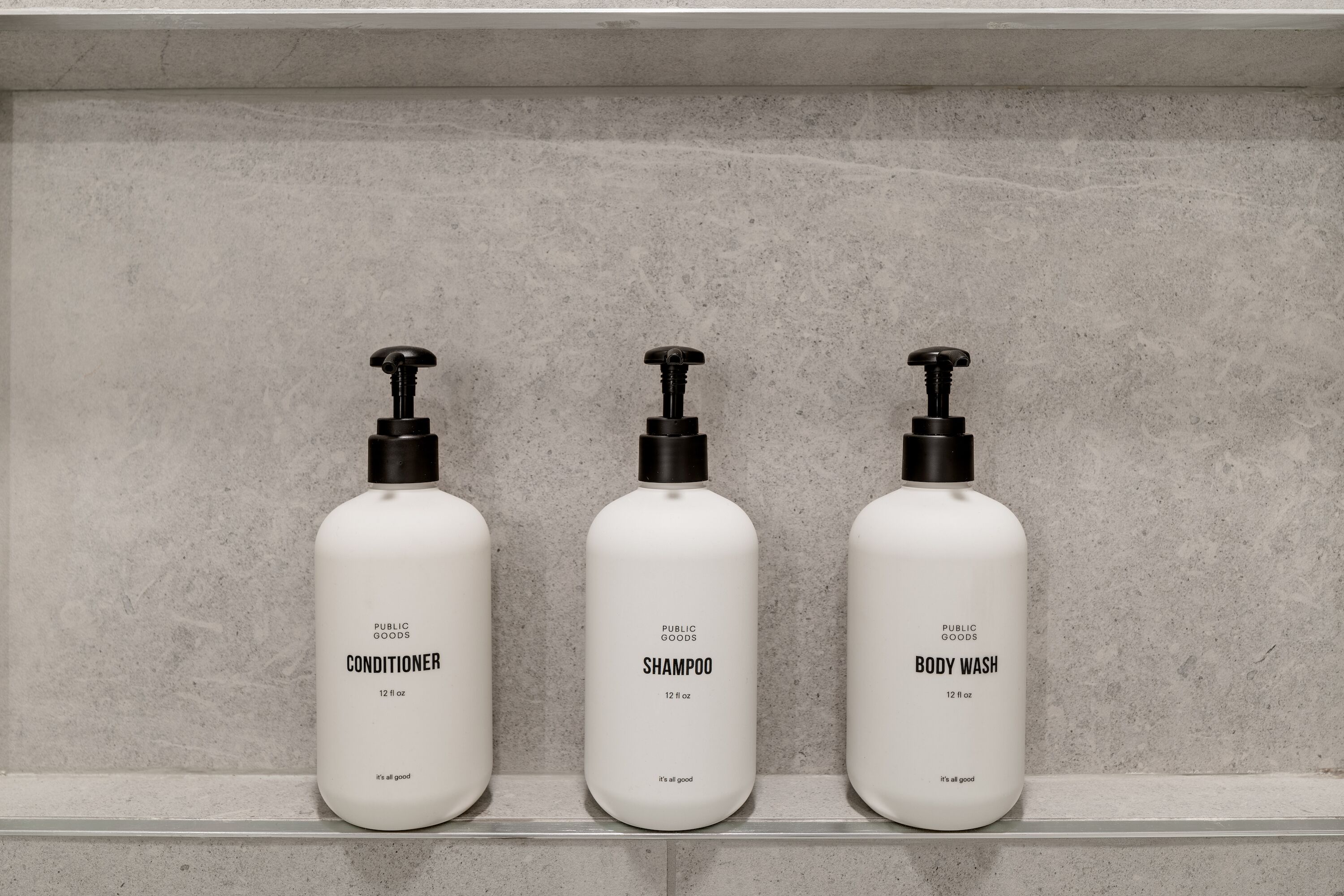 Tres botellas de productos Public Goods sobre una estantería.