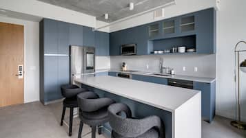 Uma cozinha moderna com uma ilha grande, banquetas, micro-ondas e geladeira.