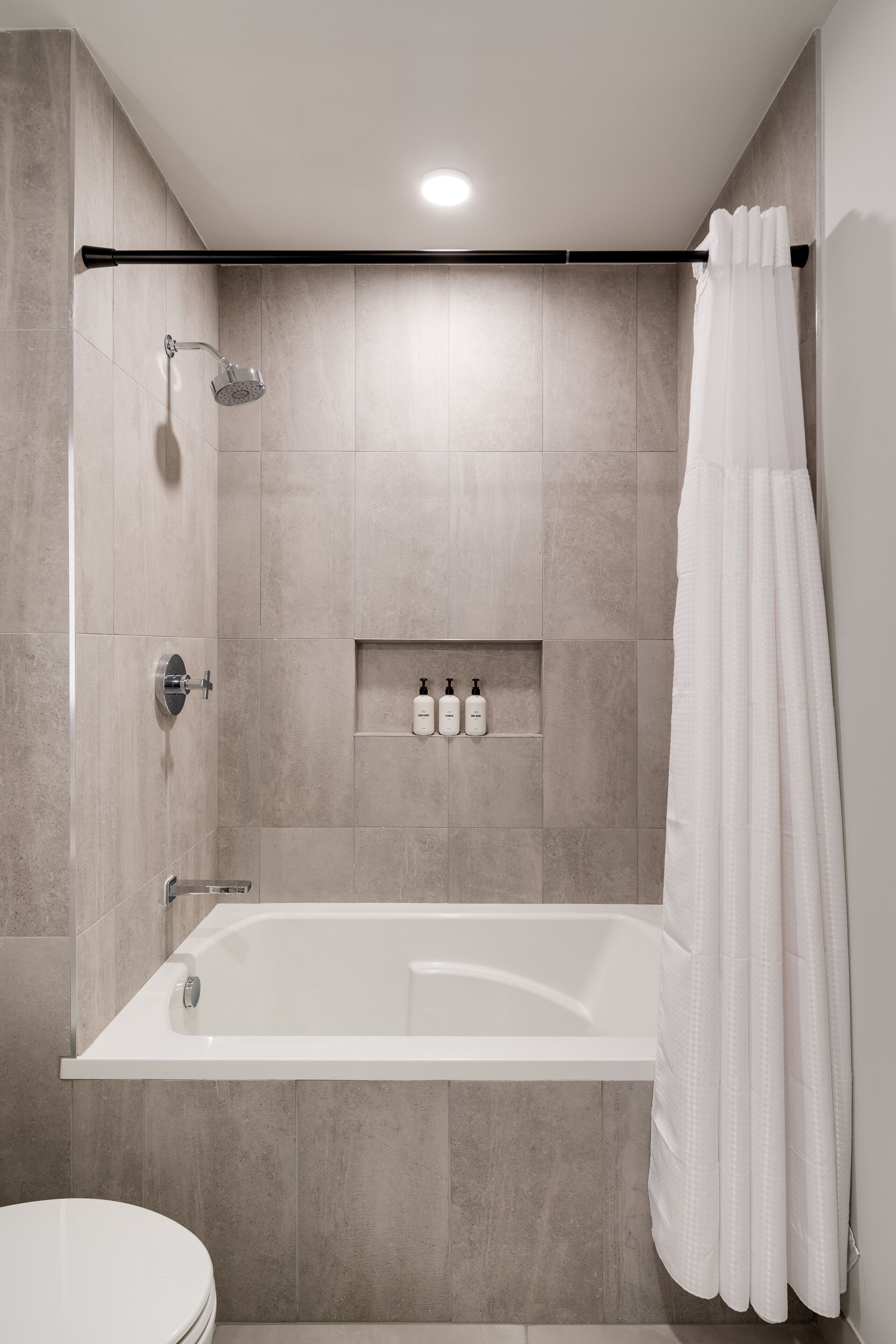 A modern bathroom with a bathtub, shower, and toilet.