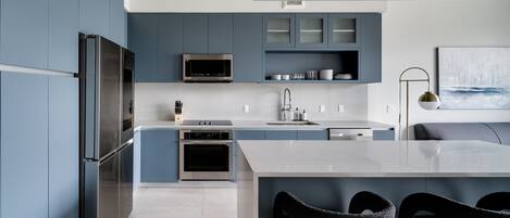 A modern kitchen with a large island, built-in appliances, and a minimalist design.