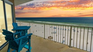 Ein Balkon mit Blick auf Strand und Meer bei Sonnenuntergang.