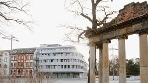 Un bâtiment moderne à la façade incurvée, avec une structure de colonnes classiques en premier plan.