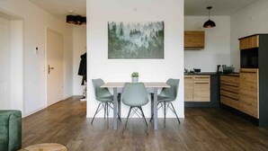 Une cuisine moderne avec des meubles en bois, un coin repas comprenant une table et des chaises, et un tableau accroché au mur.