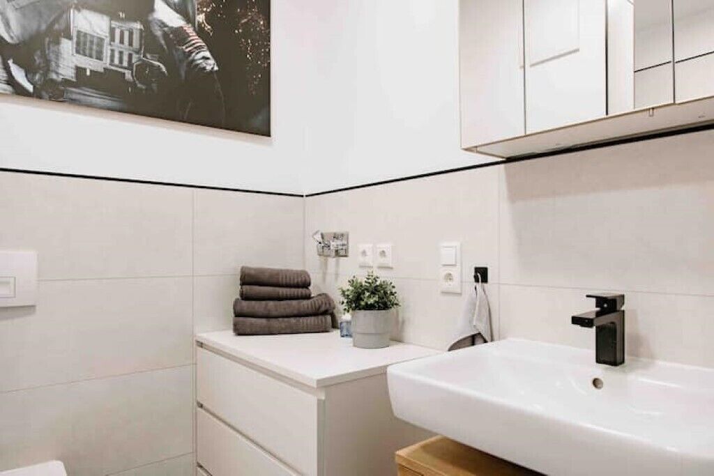 Ein modernes Badezimmer mit Waschbecken, Handtuchhalter und einer Topfpflanze.
