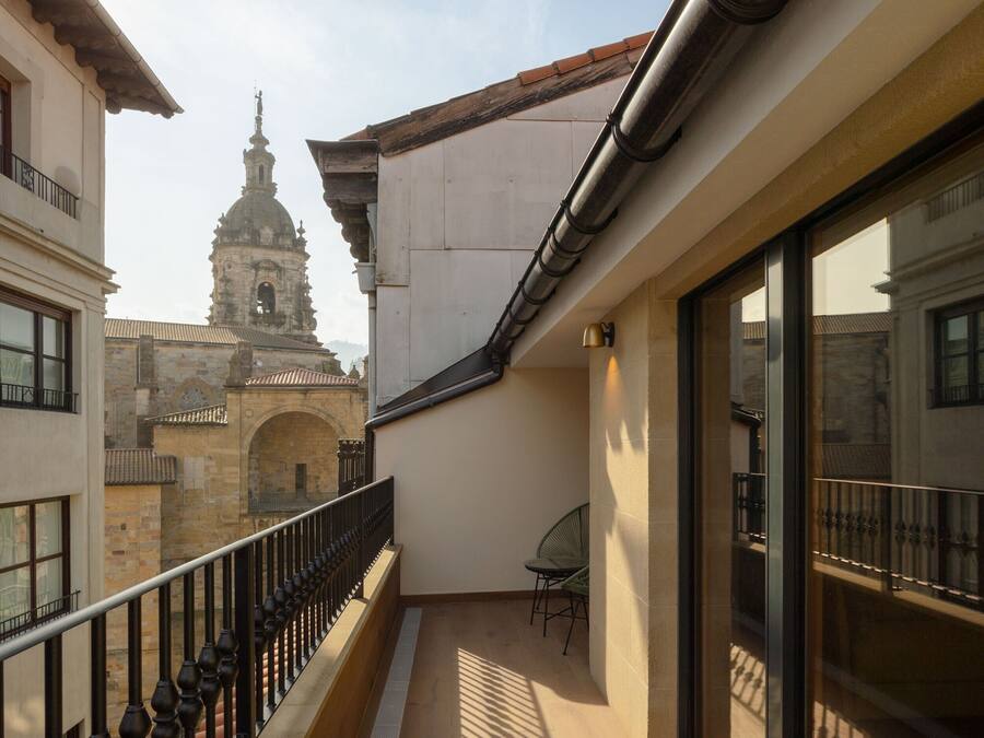 A balcony with a view of a historic building, a chair, and a railing.