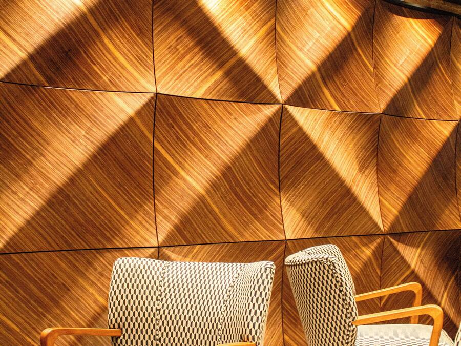 Un interior moderno con paneles de madera geométricos, sillas de estampado vichy y una mesa redonda.