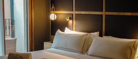 A hotel room with a large bed, two pillows, a nightstand, a lamp, and two towels with the hotel name.