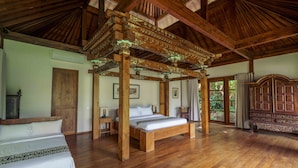Una habitación amplia con una cama grande, vigas de madera en el techo y un dosel de madera sobre la cama.