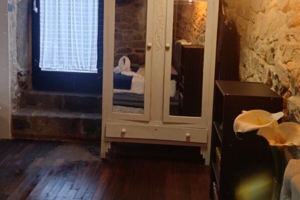 Una habitación con pared de piedra, un mueble de madera con puertas de cristal y una ventana con cortinas.