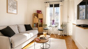 A modern living room with a sofa, a coffee table, a bookshelf, and a television. - L'appartement Blomet  (Paris)