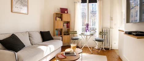 Una sala moderna con un sofá, una mesa de centro, una estantería y un televisor.