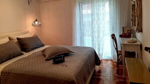 Ein Schlafzimmer mit Bett, Nachttisch, Lampe und einem Fenster mit Vorhängen.