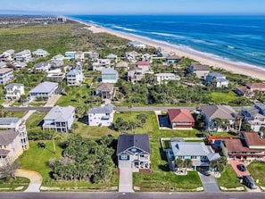 Vista aérea de una zona residencial costera con casas, una playa y cielo despejado.