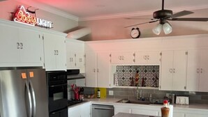 Una cucina moderna con elettrodomestici in acciaio inossidabile, mobili bianchi e un'isola centrale con sgabelli.