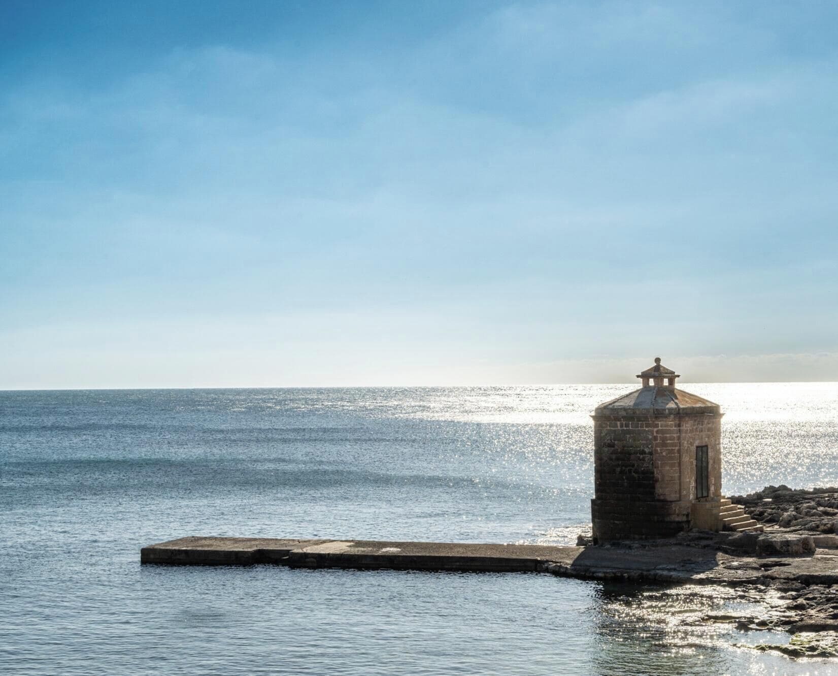 Un phare au bord de la mer, sous un ciel dégagé.