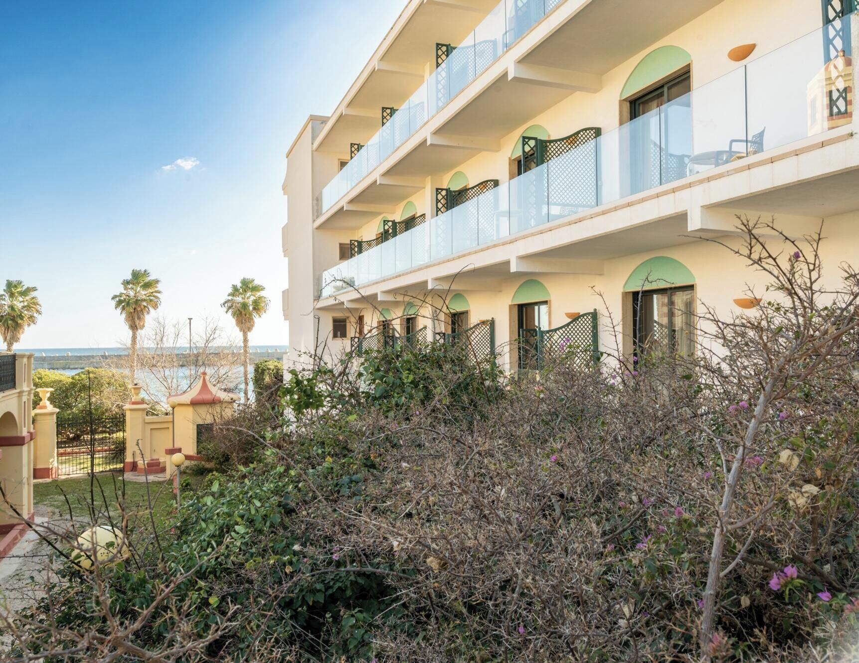 Ein mehrstöckiges Hotel mit Balkonen, einem Poolbereich und Meerblick.