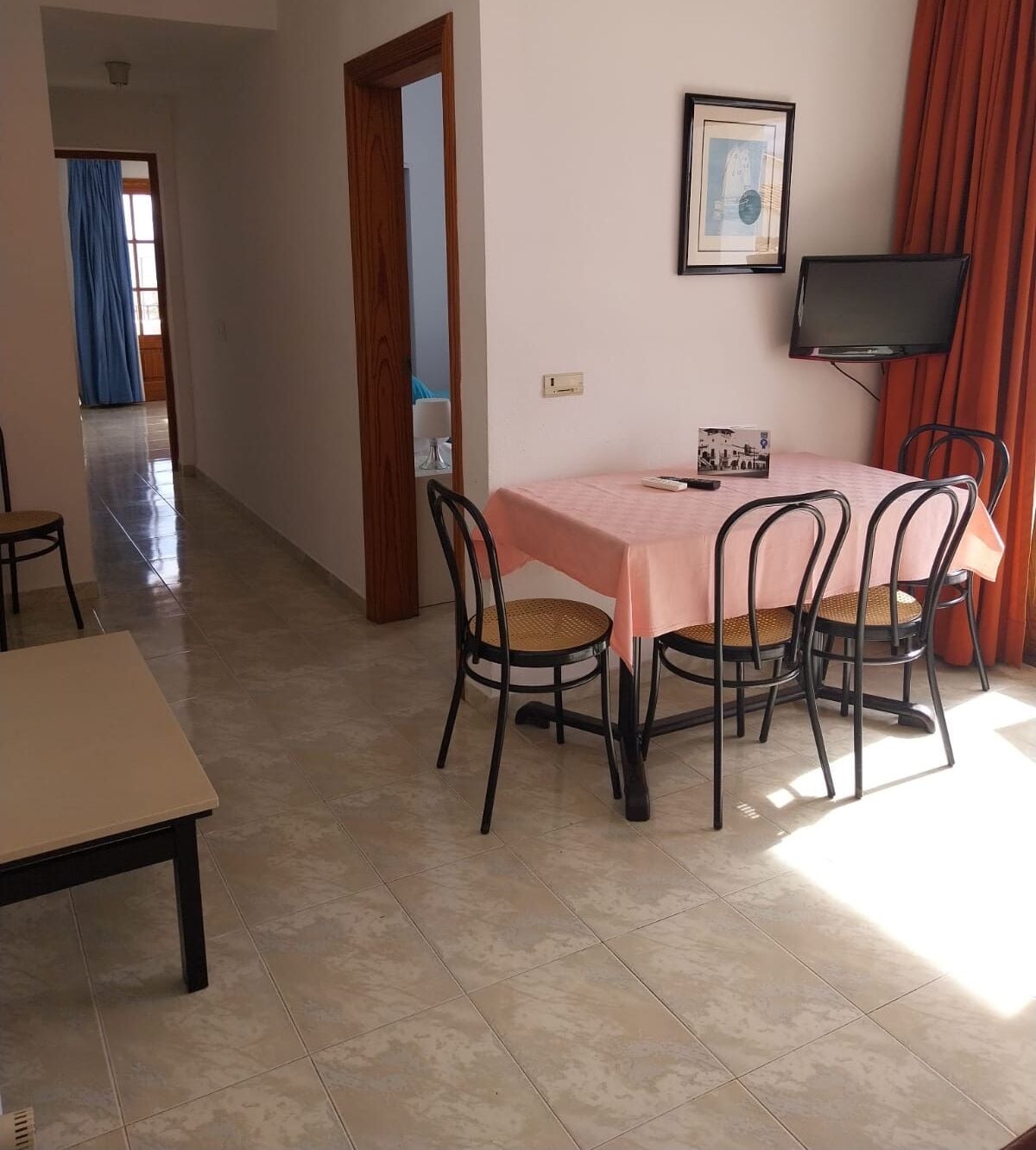 Un coin repas avec une table et des chaises, un téléviseur et un tableau encadré au mur.
