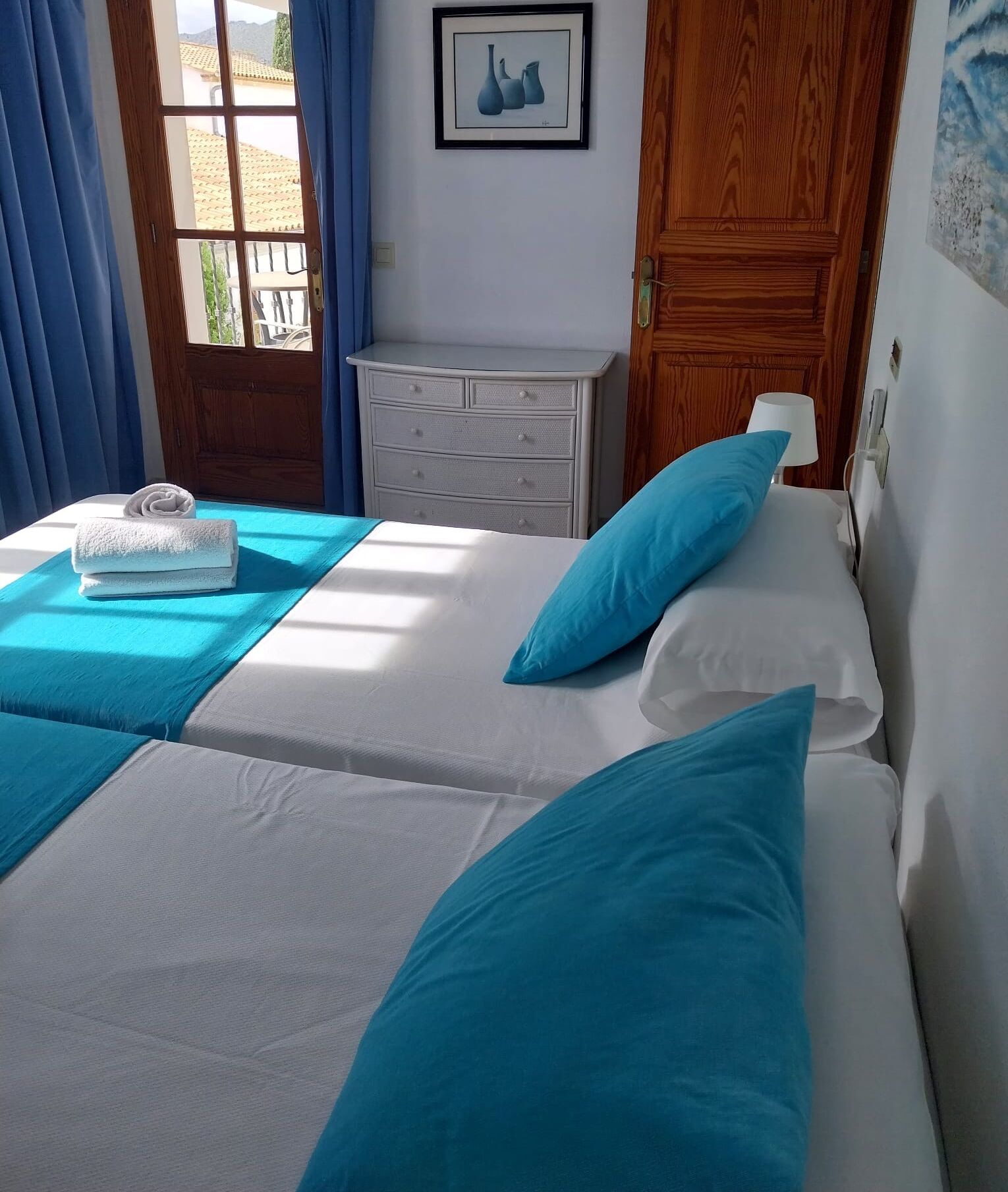 Una habitación de hotel con dos camas, un aparador y una puerta.