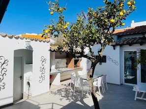 Enjoy al fresco dining and leisure time in this beautifully designed patio area with a tree, glass table, and brick oven.