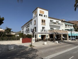 Un hotel de varios pisos con balcones y mobiliario exterior.
