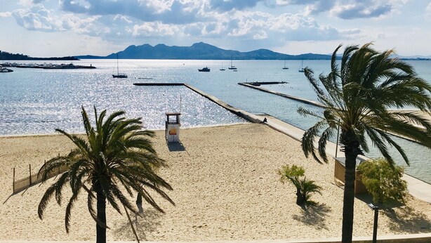 Ein Strand mit Palmen, einem Rettungsturm und Booten im Wasser.