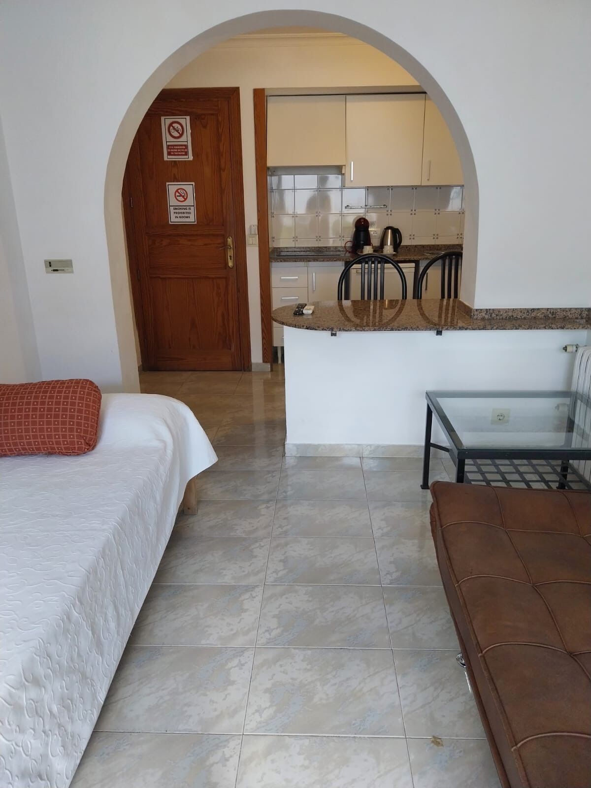 Una habitación de hotel con cama, sofá, una mesita y una kitchenette.