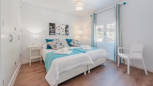 Ein Schlafzimmer mit einem Bett, Nachttischen, einem Sessel und Bildern an der Wand.