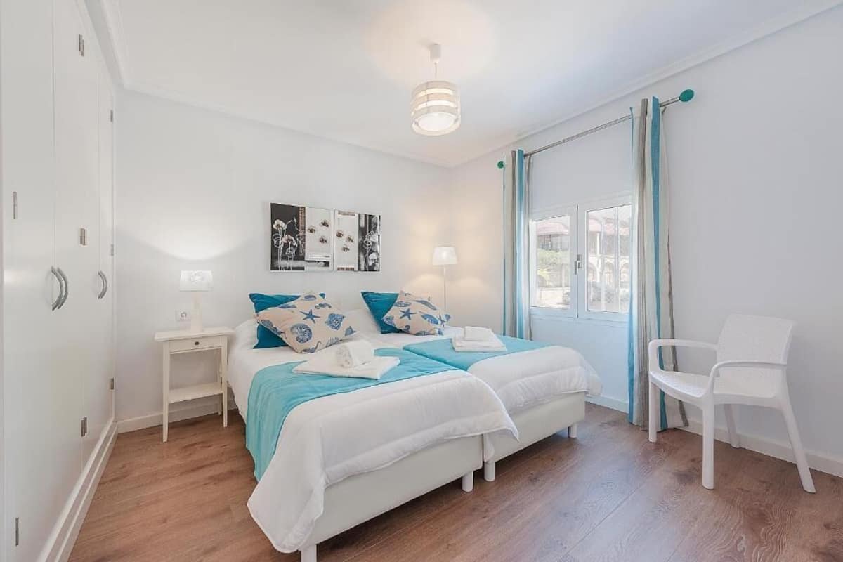 Un dormitorio con cama, mesitas de noche, una silla y una obra de arte en la pared.